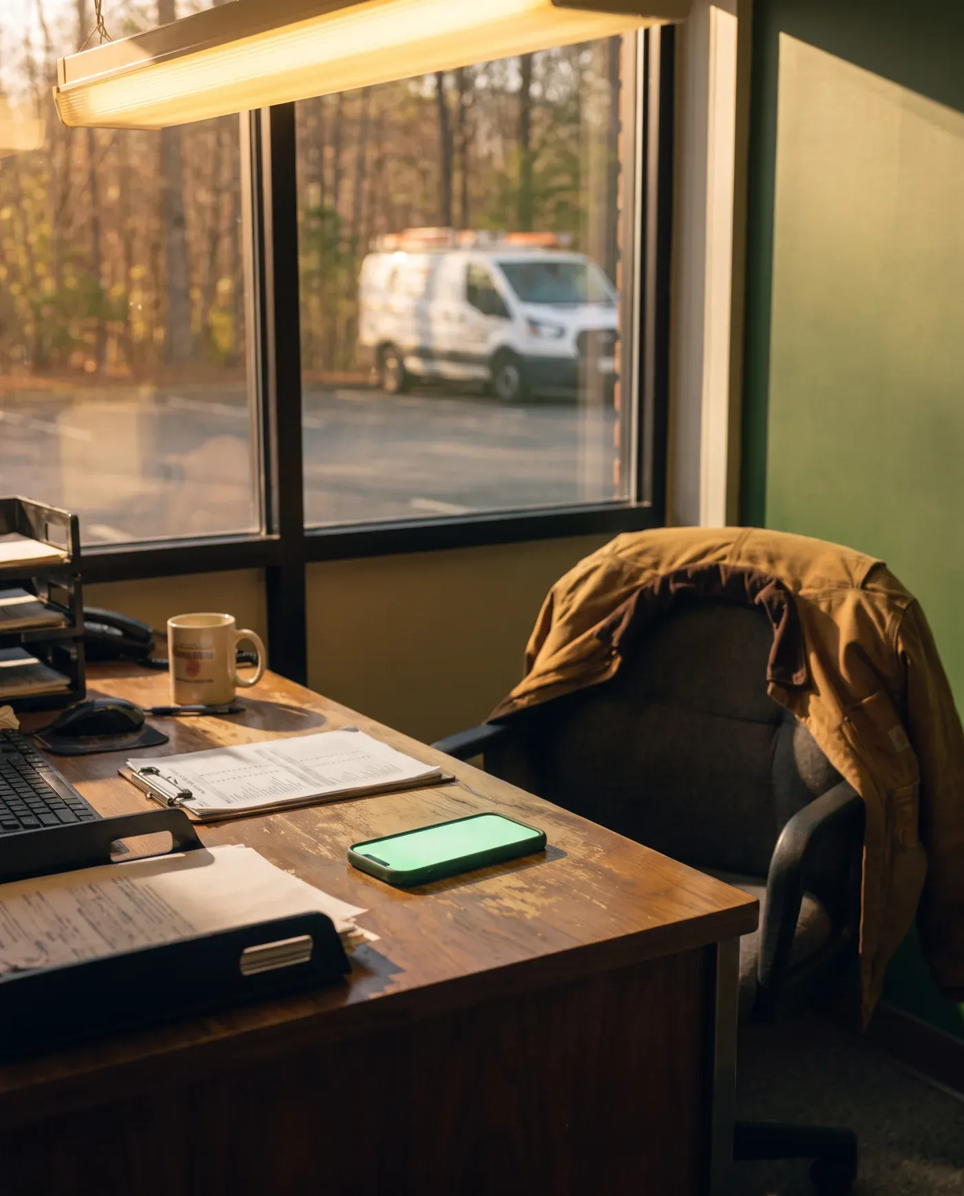 A small shop office in morning light, a white work van outside.